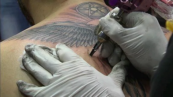 Un tatuador graba un ángel sobre la piel de su cliente.