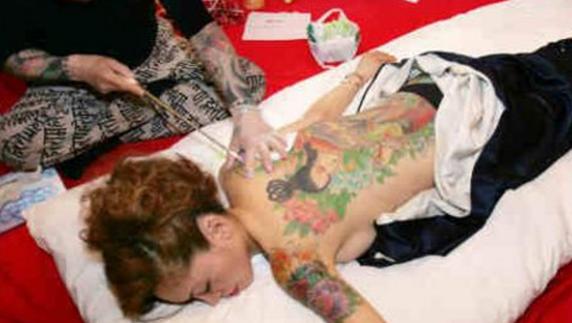 Un artista japonés Horiyoshi realizando tatuajes temporales en un club de Tokyo, Japón.