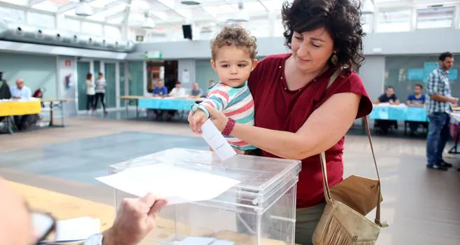 Un niño deposita el voto de su madre en una urna en Bilbao. 