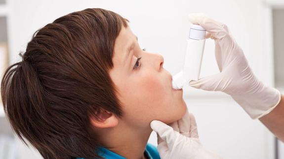 Una doctora aplica un inhalador a un niño asmático.