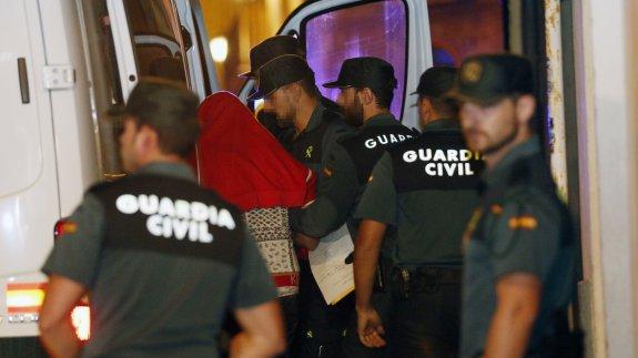 El presunto homicida con el rostro tapado con una sudadera roja, ayer, entra en el furgón de la Guardia Civil.