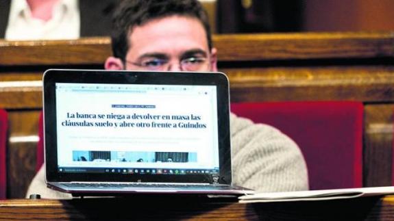 El diputado de Cataluña Si que es Pot, Albano Dante, ayer en la Cámara catalana mientras mostraba un titular alusivo a las claúsulas suelo.