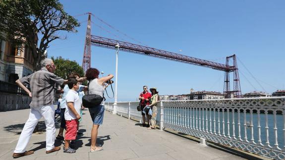 Un grupo de turistas se fotografía frente al Puente Colgante. 