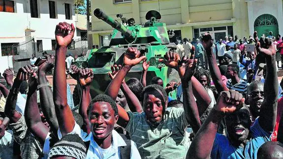 Vecinos de la capital de Gambia celebran la marcha del dictador vigilados por fuerzas militares.