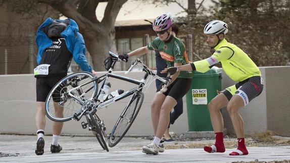 Dos participantes tratan de retener una bicicleta arrastrada por el viento. 