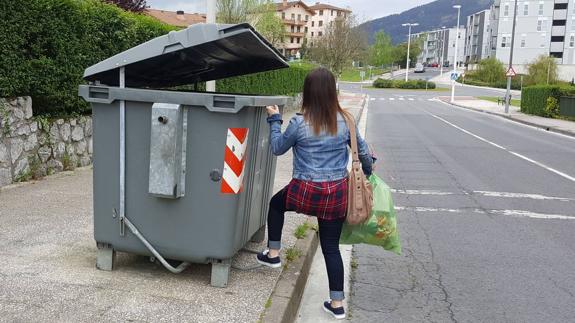 Una mujer deposita la basura en un contenedor en Llodio.