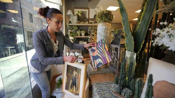 Una comerciante de Bermeo decora el escparate con obras de artistas locales. MAIKA SALGUERO