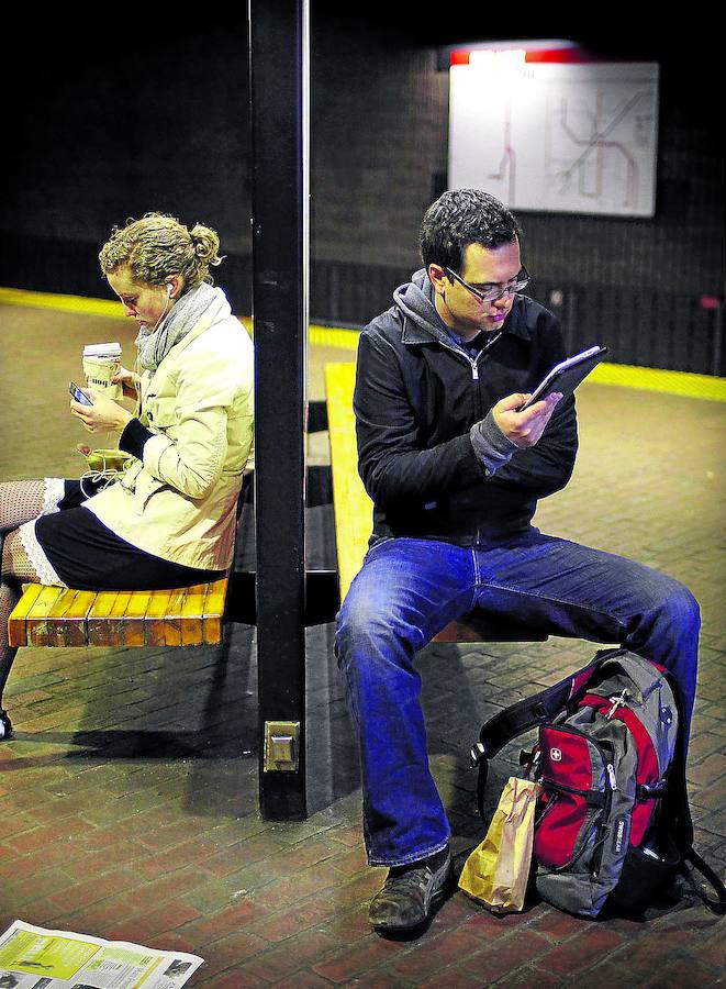 Un joven estadounidense lee un libro digital en su ‘ebook’ mientras espera al metro.