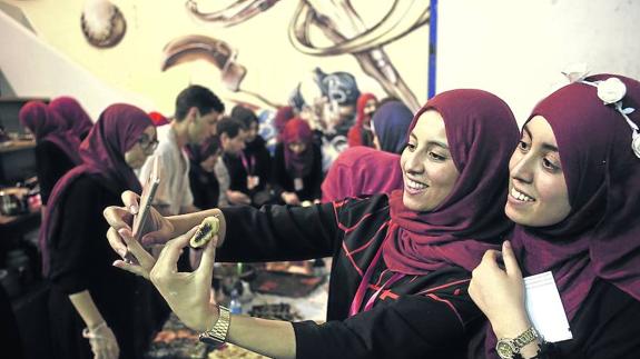 Dos de las jóvenes organizadoras del ‘iftar’ de este año se fotografían con la comida, al inicio del evento.