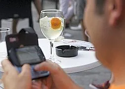 Un joven consulta su teléfono mientras degusta un gin-tonic.