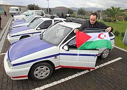 Un hombre coloca una bandera del Sáhara en uno de los vehículos donados./ Telepress