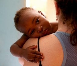 Una cooperante atiende a un niño huérfano por el sida en África. / EFE