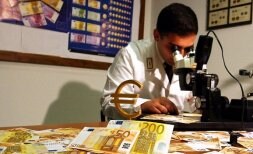 Un 'carabinieri' italiano observa a través de un microscopio billetes sospechosos de ser falsos. / AP