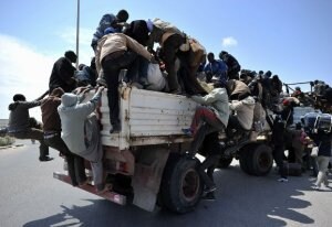 Decenas de inmigrantes africanos se suben a las camionetas que los llevarán al puerto de Bengasi para huir de Libia. ::                             AFP
