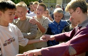 Una pareja de adolescentes juega a golpearse las manos en el patio de un colegio. :: AP