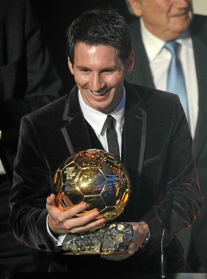 Messi, muy sonriente sostiene en las manos su tercer Balón de Oro. ::                         AFP