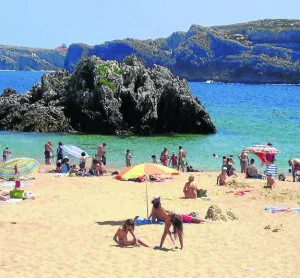 Veraneantes disfrutan del buen tiempo en la playa de San Juan de la Canal. ::                         E. C.