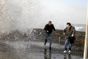Una ola sorprende a dos personas que se hacían una foto en San Sebastián. /G. Rivas