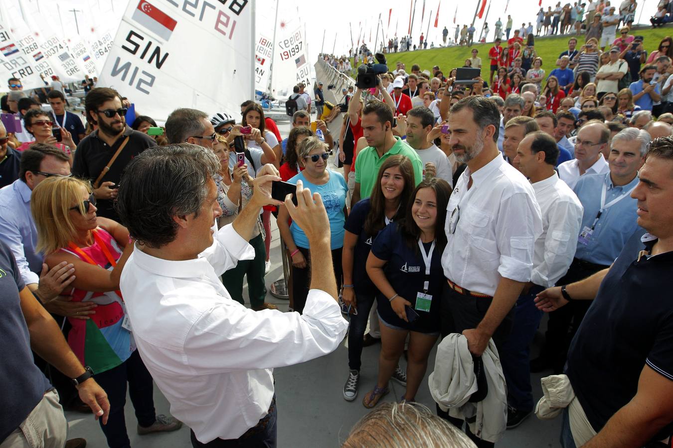 El alcalde, Íñigo de la Serna, toma el móvil de una joven para hacerle una foto con el Rey durante la celebración del Campeonato Mundial de Vela Santander 2014