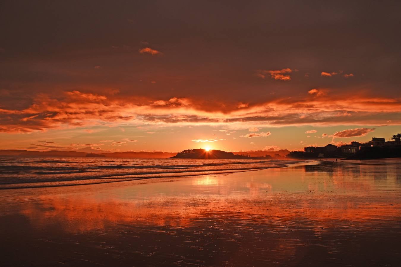 Al atarceder y con el sol escondiéndose por la península de La Magdalena, El Sardinero muestra un cielo de color intenso.