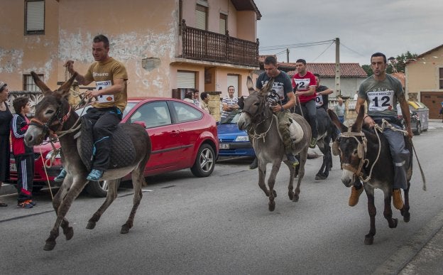 Escenas de la tradicional carrera de burros de Tanos, que ayer alcanzó su edición 57 con la presencia de cientos de personas. A la derecha, poco ambiente en el recinto ferial debido al mal tiempo. 