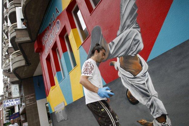 Un integrante de la asociación Mens Rea durante el pintado del grafiti que decora la fachada de la Casa de la Juventud. 
