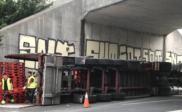 Varias personas extraen los palés del camión siniestrado.