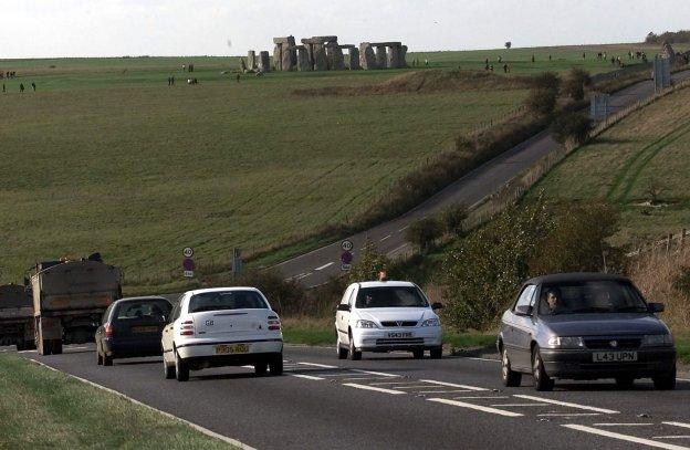 Los vehículos circulan por la carretera próxima a Stonehenge, que se recorta contra el horizonte