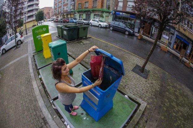 Una mujer recicla basura en contenedores específicos para cada tipo de residuo.