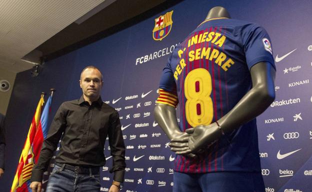 Iniesta, junto a una camiseta conmemorativa de su renovación vitalicia. 