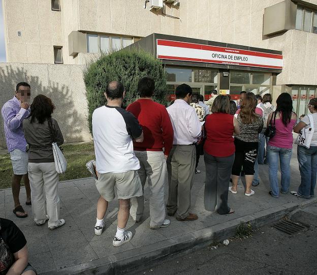 Varias personas en la cola de una oficina de empleo. 