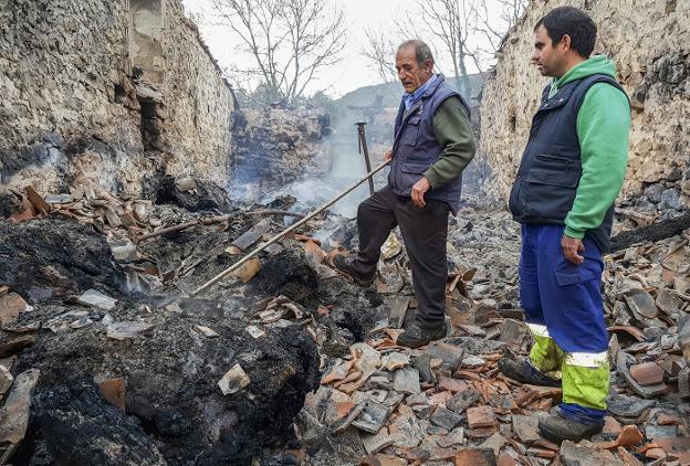 Arturo Nebreda, en primer plano, y su suegro, Jacinto Salas, observan el estado en el que ha quedado la cuadra tras el incendio. 