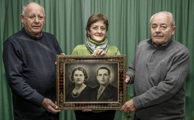 Antonino Herrera, a la izquierda, junto a Paz Herrera y su padre, Pedro Herrera, sostienen la imagen de Ángel Herrera y su mujer. 