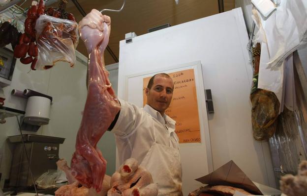 Un carnicero muestra un conejo listo para ser consumido. 