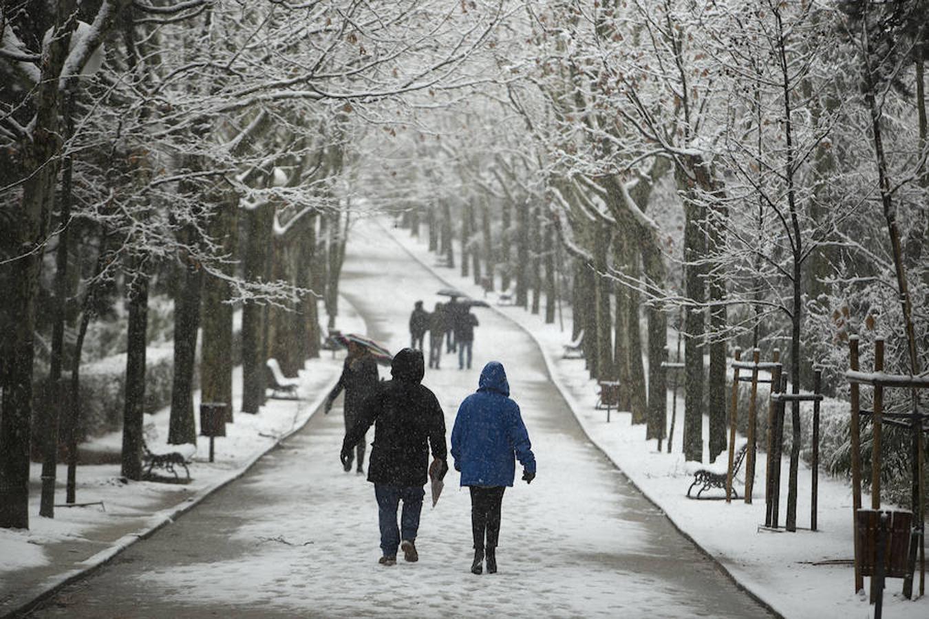 Una pareja pasea por un parque de la capital cubierto de nieve.