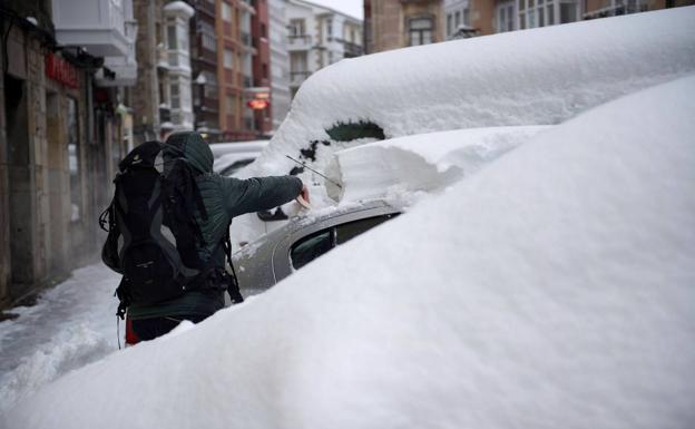 Un reinosano quita la nieve de su coche.