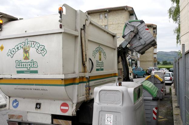 Un camión recoge residuos orgánicos depositados en un contenedor de basura.