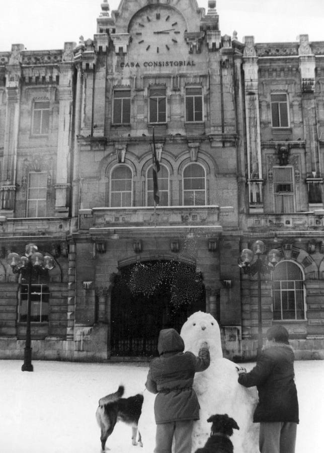 Dos personas haciendo un muñeco de nieve frente al Ayuntamiento de Santander.