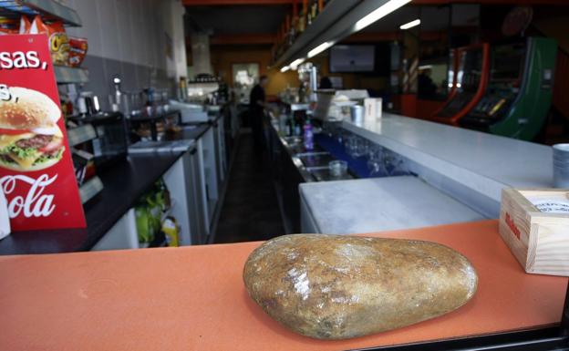 En primer plano, la enorme piedra con la que rompieron el cristal de la puerta del bar.