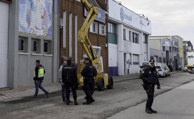 Policías y trabajadores esperan en el exterior de una de las naves de Raos mientras dentro se lleva a cabo un registro.