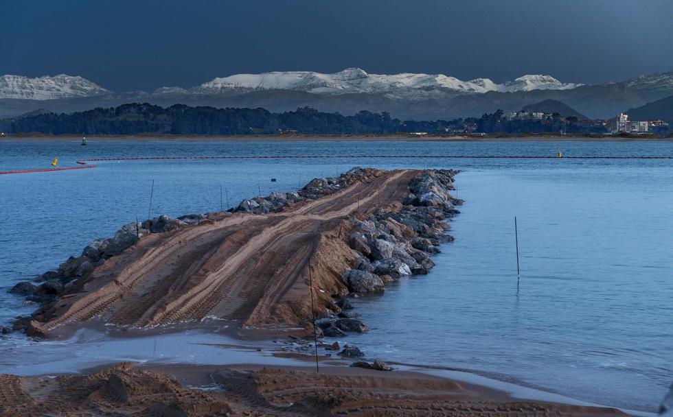 El nuevo dique de La Magdalena, con las huellas frescas de las rodadas de las máquinas, se adentra en la bahía, con las montañas pasiegas nevadas como telón de fondo.