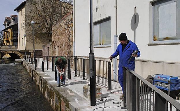 Dos operarios trabajan en la instalación de la barandilla de seguridad junto al río Ebro