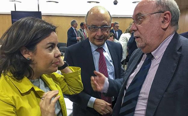 Soraya Sáenz de Santamaría y Cristóbal Montoro conversan con Juan José Sota este verano en Madrid.