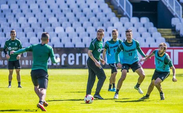 Los jugadores del Racing se ejercitan en la sesión de ayer, con la grada vacía de los Campos de Sport al fondo. 