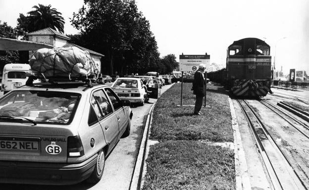 El embarque: Imagen del año 1988, con los trenes aún atravesando el muelle por la ciudad y la cola de coches con matrícula británica para acceder al barco ante la antigua gasolinera. :