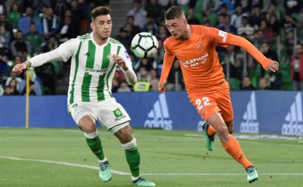 El delantero del Betis Antonio Sanabria pelea un balón con el centrocampista belga del Málaga, Maxime Lestienne.