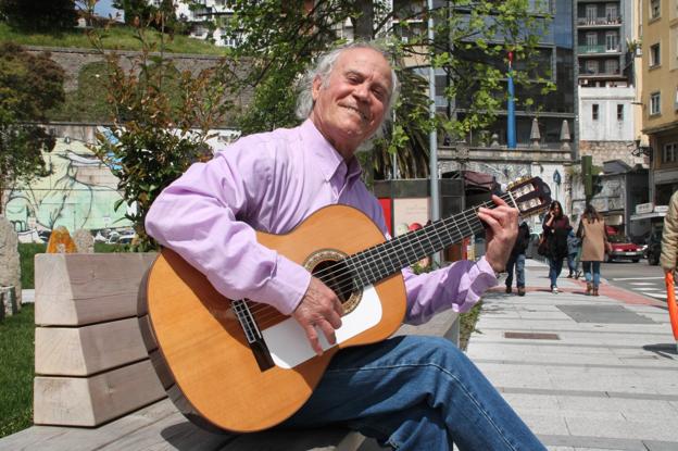 El cantautor Manuel Iberia, con su guitarra, en un banco de la Plaza de las Estaciones en Santander.