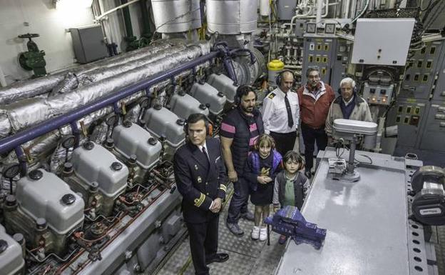El comandante y el jefe de máquinas muestran a los visitantes la sala de motores del remolcador de la Armada Española.