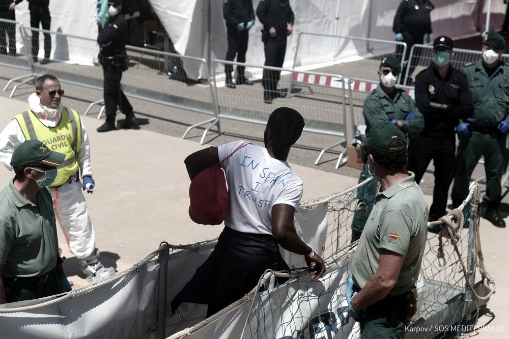 Un inmigrante se baja del barco Aquarius el pasado domingo en Valencia con una camiseta en la que se puede leer 'In Spain I trust', en 'España yo confío'