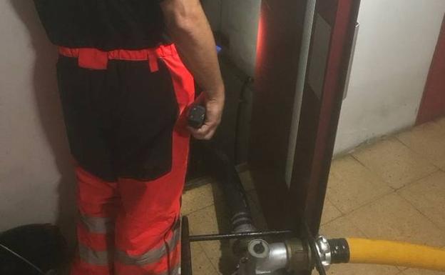 Bomberos achicando el agua en el hueco de un ascensor en Treceño.